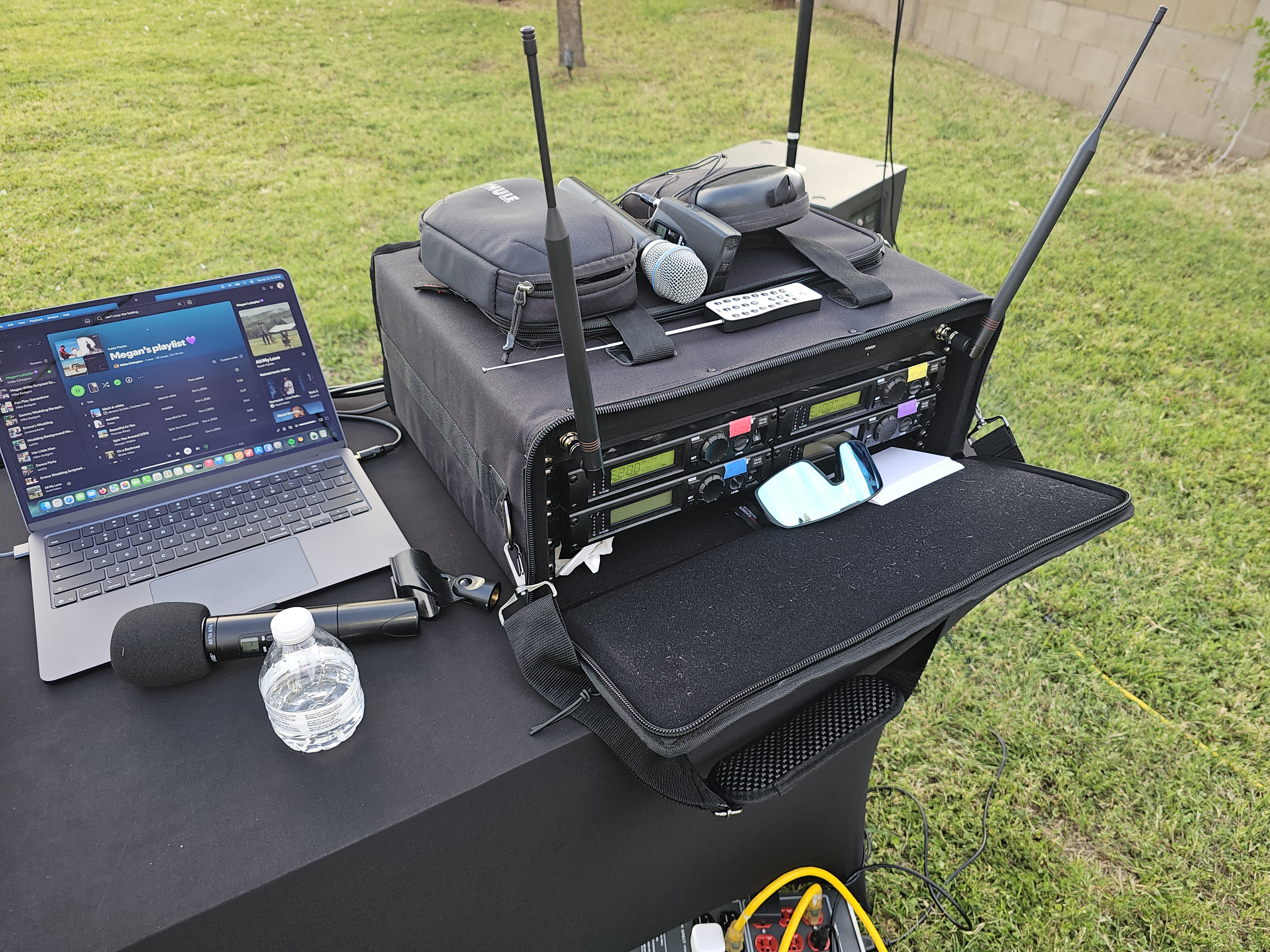 Organized DJ setup with wireless mic rack and laptop