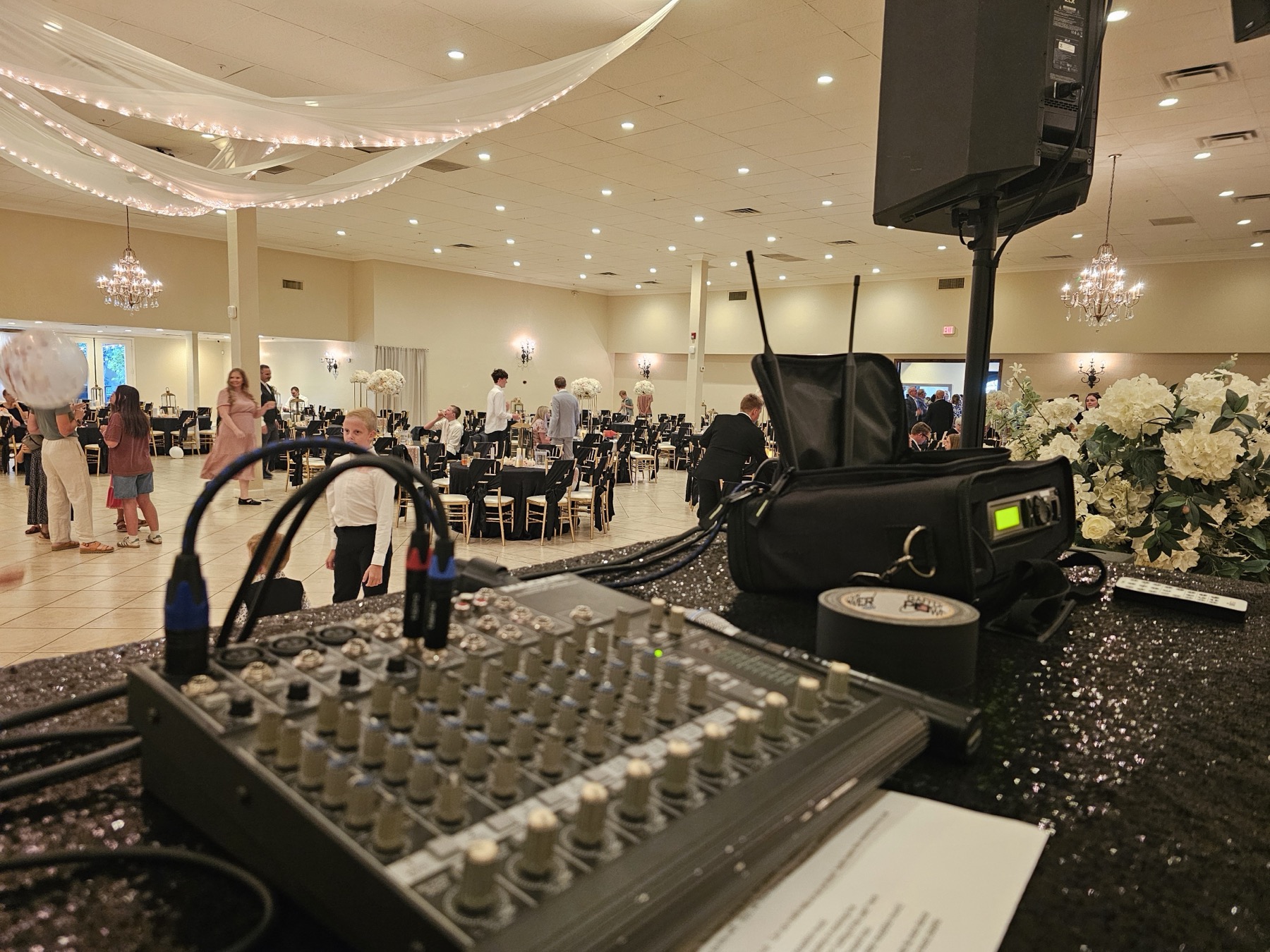 DJ booth view of mixer and wireless gear overlooking a large ballroom venue